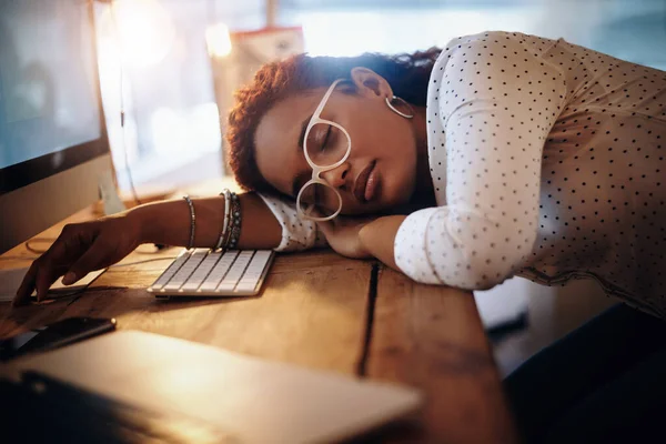 I could use a power nap... a young businesswoman sleeping at her desk while working in an office at night