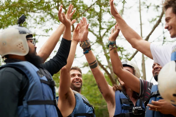 This is for being an adventurer seeker. a group of young male friends giving each other a high five before they go white water rafting