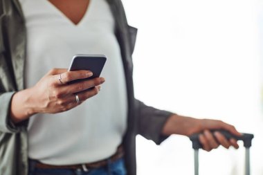 Texting people back home that I arrived safely. an unrecognizable woman using a cellphone in an airport