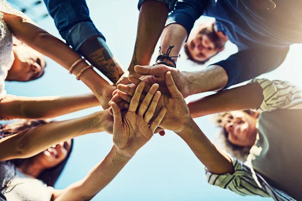 Sharing a solid friendship. Closeup shot of an unrecognizable group of people joining their hands in a huddle outdoors