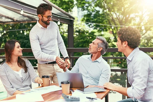 Their team just keeps growing and growing. two businessmen shaking hands during a meeting outdoors