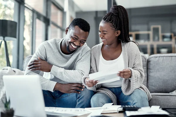 Happy black couple paying bills on a laptop at home, checking their budget and savings. Smiling African american husband and wife enjoying future planning, excited about an investment and good credit.