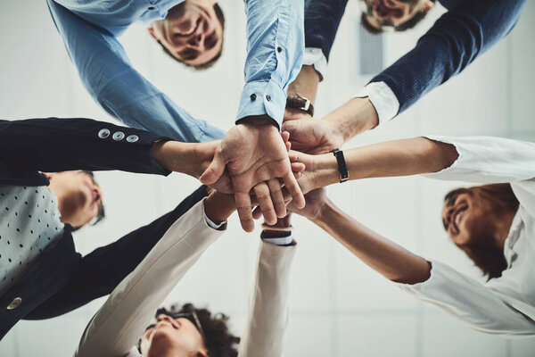 Team of business people hands stacked showing teamwork, collaboration and standing united for project development and innovation. Group of corporate colleagues joining in support and unity from below.