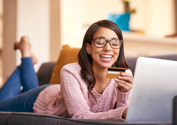 Shes the first to scoop up the latest deals. an attractive young woman using a laptop and credit card on the sofa at home