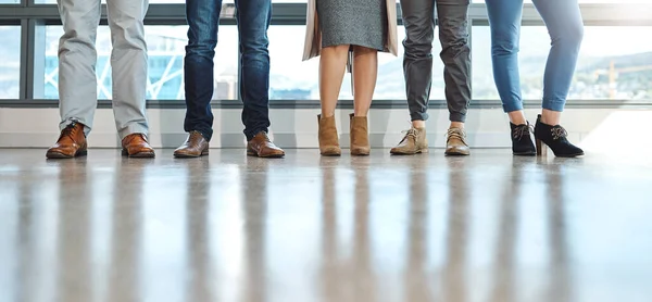 United we stand in business. a group of unrecognizable businesspeople standing in line in an office