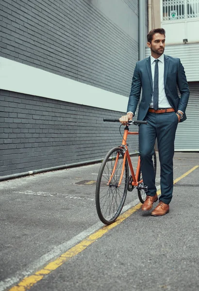 Doing his bit to leave a cleaner footprint. a handsome young businessman standing alongside his bike outdoors