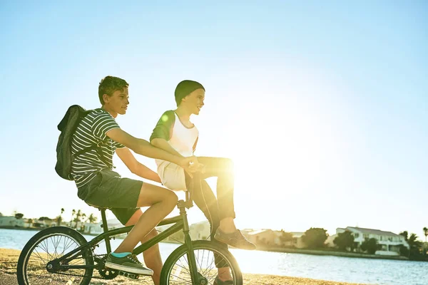 Brothers on a bike. a young boy giving his younger brother a lift on a bicycle outside