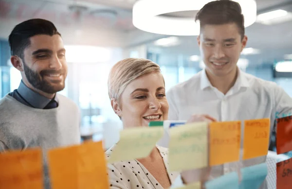 Lets Brainstorm Three Young Businesspeople Brainstorming Sticky Notes Glass Wall — Stok fotoğraf