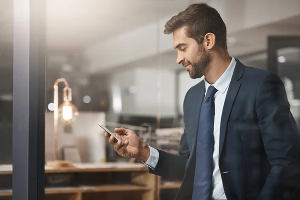 Text updates are the easiest to work from. a young businessman using a cellphone while working late in an office