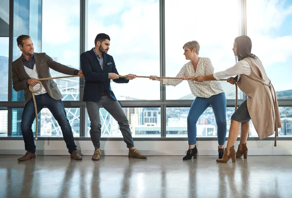 Only the strong survive in business. a group of businesspeople pulling on a rope during tug of war in an office