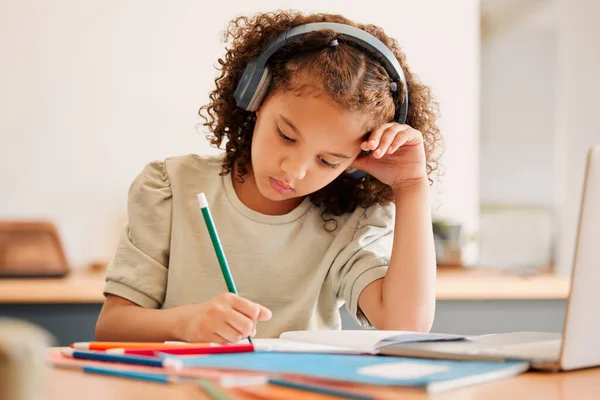 Smart school child, student virtual learning while writing in her book inside an education classroom. Creative with headphones drawing art on paper. Cute, artistic little kid doing homework.