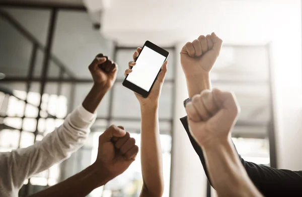 Hands of business people cheering, celebrating good news on a phone with blank screen for copy space. Excited team of office workers showing power fist gesture for success, victory and winning.