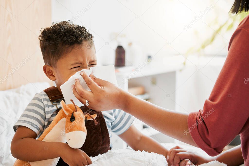 Flu, sick or cold child with parent sneezing, blowing and wiping runny nose while ill with covid virus, sinus and allergy symptoms in bed at home. Mother caring for stuffy and congested little son.