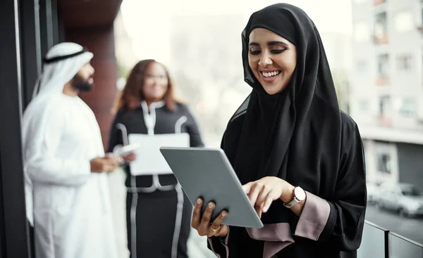 Everything she needs at the touch of a button. an attractive young businesswoman dressed in Islamic traditional clothing using a tablet on her office balcony