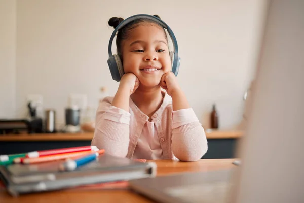 Distance learning, education and online lesson with girl wearing headphones and laptop webcam. Kindergaten or primary school Student studying with virtual video internet class with a teacher at home.