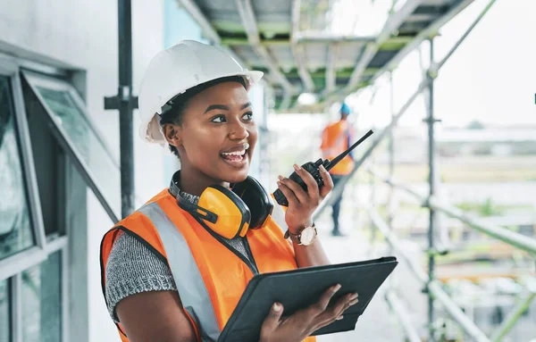Construction worker with tablet, walkie talkie or radio talking, instructing and checking building progress on development site. Architect manager, female leader or engineer watching infrastructure.