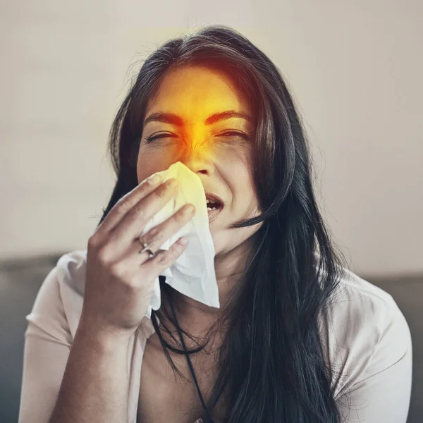 No stop to these sneezes. a young woman blowing her nose at home