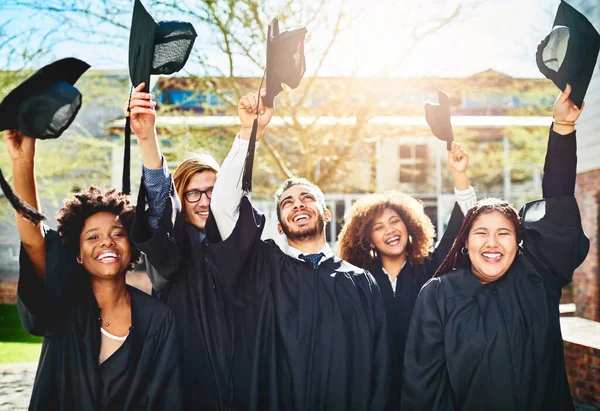 Were ready to take over the future. a group of students throwing their caps into the air after graduating