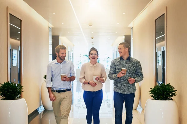 Even the best need a break from time to time. Portrait of a group of young businesspeople walking together down a passage while drinking coffee