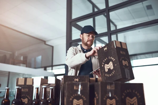 One package to be delivered for one lucky person. a cheerful young man packing boxes on top of each other inside of a office building during the day