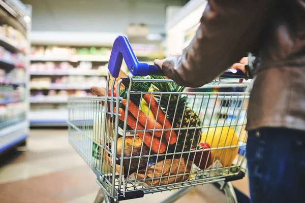 Her grocery store of choice. a woman pushing a trolley while shopping at a grocery store