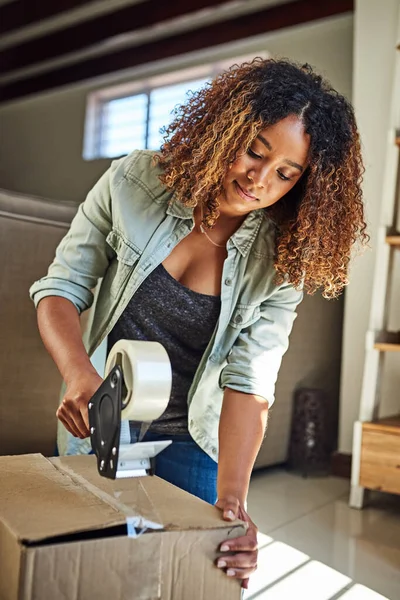 Im putting you away until I need you again. a confident young woman taping a box closed to put it away in storage after moving into a new home