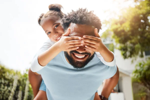 Fun father playing with his young daughter on his back in their family home garden bonding together. Small child laughing and enjoying happy, silly childhood lifestyle with loving parent.