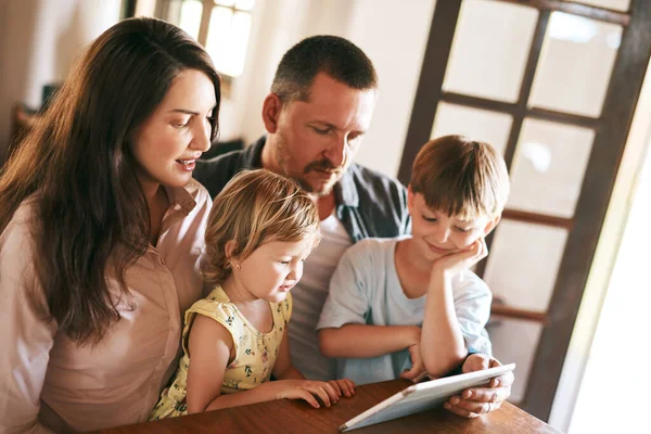 In the digital age, family time is screen time. a young family of four using a digital tablet together at home