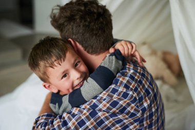 I love my dad. High angle portrait of an adorable little boy embracing his dad in his bedroom at home