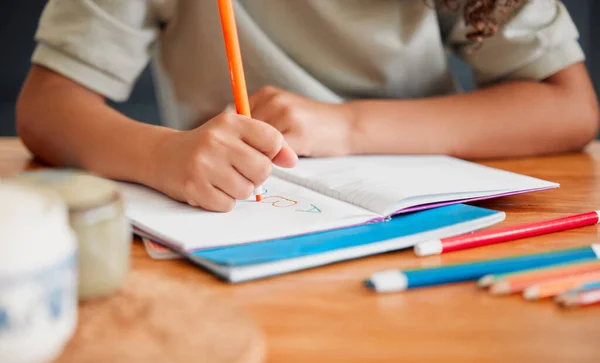 Child coloring, drawing and doing art activity in book in home living room while having fun, enjoying and feeling playful. Closeup hands of small, little and young creative girl expressing with color.