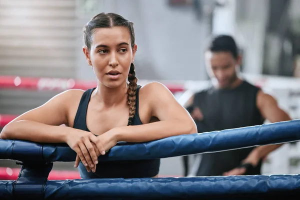 Fit, active and tired boxer taking break, resting and breathing after workout, training and exercise with boxing coach in ring. Sporty, athletic or strong woman after kickboxing fight or sports match.