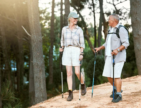 Hiking, adventure and exploring with a senior couple or friends having fun, exercising and enjoying the outdoors. Walking, discovering and journey with old people talking in nature, forest or woods.