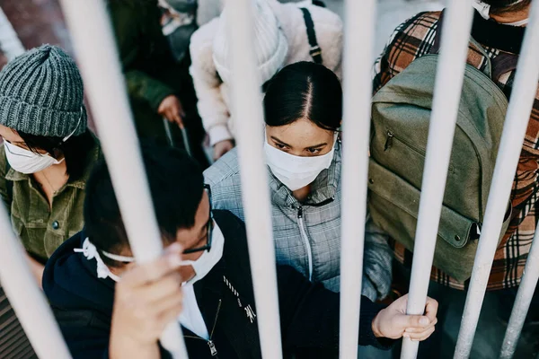 Covid travel ban, lockdown or border control to prevent spread of pandemic virus, contagious disease or illness. Travelers in masks facing quarantine, abuse and discrimination behind locked gate.