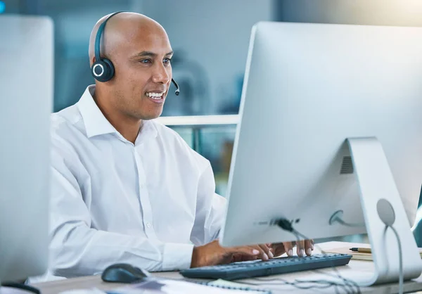 Professional, friendly customer service or sales consultant agency worker working with headset and desktop. Smiling male employee consulting with a client at call center or contact us helpdesk.