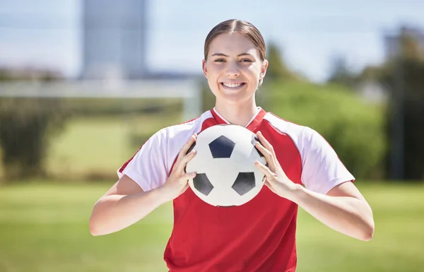 Soccer player, ball and young woman happy to play a fun sports game in a practice stadium field in summer. Exercise, training and workout of a healthy, fitness and athlete smiling on a grass pitch.