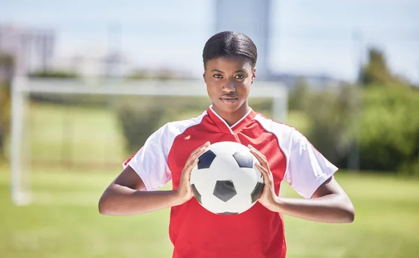 Soccer, football and sports with player, woman and athlete ready for a match, game or competition with ball on a pitch, field or stadium outdoor. Portrait of serious black female ready for training.