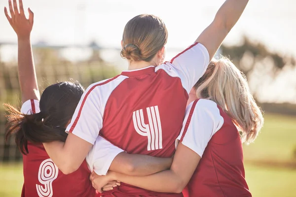 Female football team celebrating winning, goal or teamwork effort at a game, tournament or during practice on a field outdoors. Behind of women with arms raised in celebration, victory and joy.