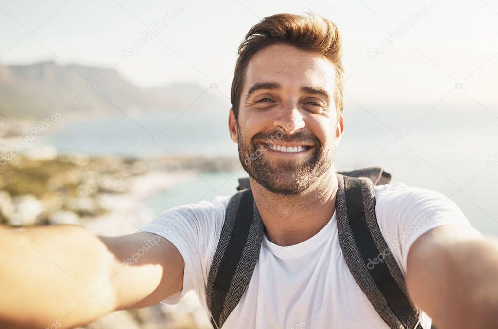 Smiling at the summit. Cropped portrait of a handsome young man taking selfies while hiking in the mountains