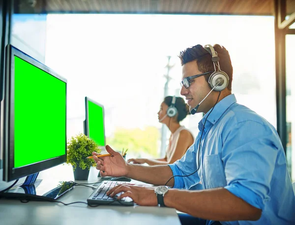 The best team to handle your queries. a young man and woman using computers with green screens in a call center
