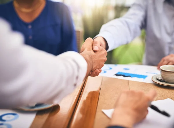 Im glad we both agree on that. two unrecognisable businesspeople shaking hands in agreement over a table at a coffeeshop