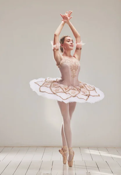 Female ballerina doing ballet dance, dancing or performing during a practice rehearsal in studio. Young dancer or artist in a tutu costume dress and shoes doing pointe technique on toes performance.