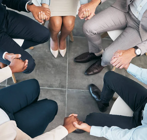Support, teamwork and unity of business group holding hands and sitting in a circle doing a team building plan. People, team or diverse employees united in trust during a meeting in an office.