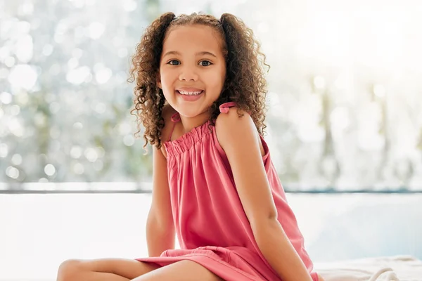 Happy child, cute curls and girl with adorable, sweet and happy smile relaxing at home. Portrait of comfortable, fun and young kid growing with healthy development, youth and adolescence.