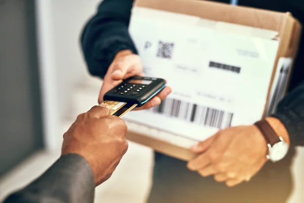 Its another convenient way to pay for deliveries. Closeup shot of a businessman using a credit card to pay for a delivery made by a courier
