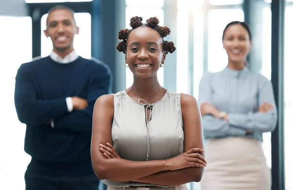 Leadership, female empowerment and proud business woman standing with her team and smiling with her arms crossed. Portrait of happy young black leader with a positive vision and mindset.