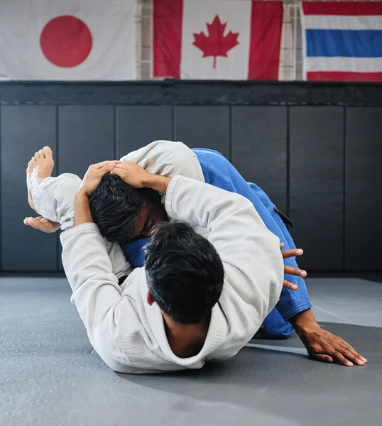 . Male martial arts, fighting at a dojo and holding his opponent. Karate, sports and taekwondo adults training at the gym for a fight. Athlete, aikido and practicing for an international competition