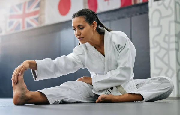 Exercise, fight and workout stretch of a karate school student with focus before training start. Sport woman or coach stretching for an exercise at a dojo studio, performance gym or martial arts club.
