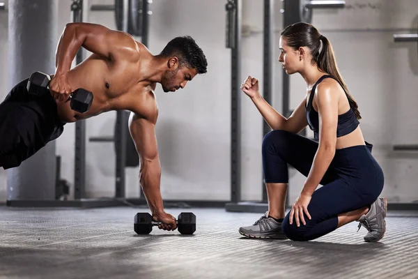 Training, exercise and motivation with a fitness coach or personal trainer and her bodybuilder student during a workout in the gym. Health, sports and wellness with a heathy athlete exercising.