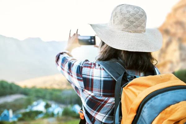 Hiking woman taking photo on adventure with phone in nature, making memories on hike and enjoying the beautiful view in the countryside on vacation. Person taking pictures of the natural environment.