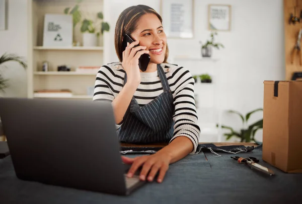 Female fashion entrepreneur on a phone call taking online packaging order for new tailor design or dress. Happy small business owner seamstress with dispatch box, making sales talking on a cellphone.